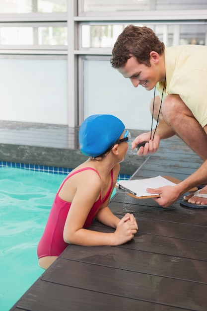 Zwemcoach die tijd laat zien aan klein meisje