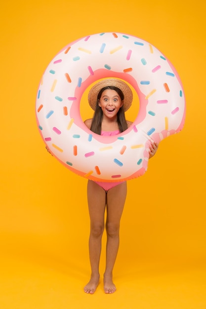 Zwemmen en zonnebaden. Rust aan zee. Zwemfeest. Gelukkige jeugd. Vermaakconcept. Klein meisje en zwemmende donutring. Kid in zwembroek met leuke wateractiviteiten. Zomervakantie.