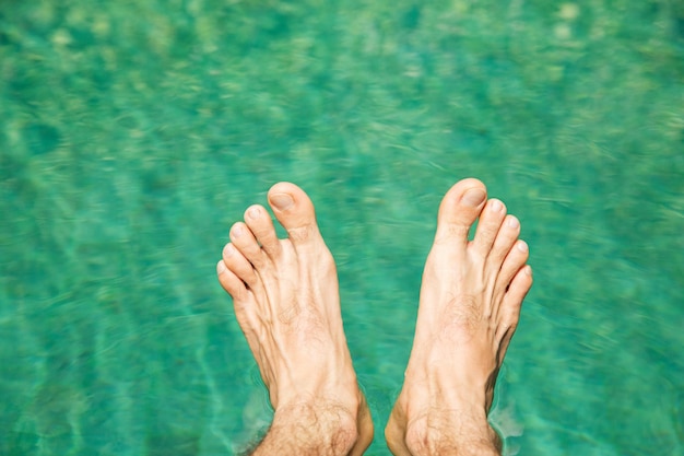 zwemmen, mensen en zomervakantie concept - mannelijke voeten over zeewater