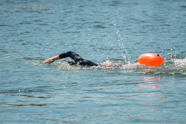 Zwemmer in wetsuit met boei in rivierwater