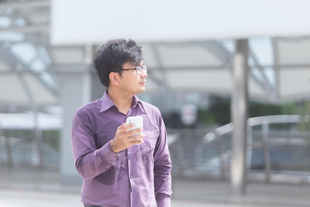 Zwetende jonge aziatische zakenman die naar berichten op mobiel kijkt