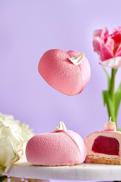 Zwevende moussecakes op een roze achtergrond in een compositie met bloemen