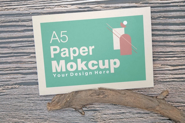 PSD a5 paper greeting card mockup with dry leaves on wooden background