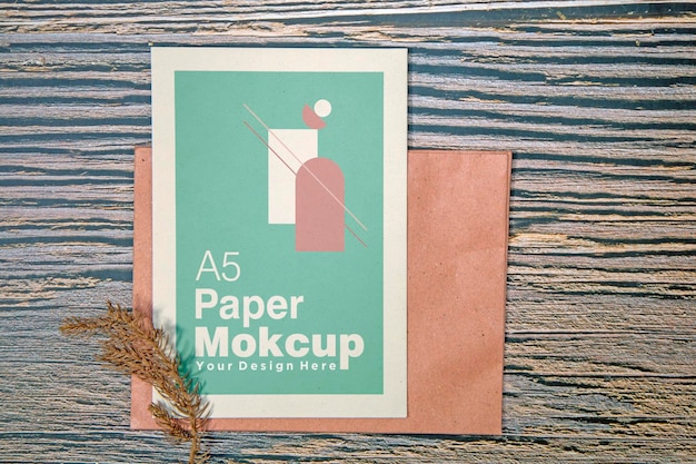 A5 paper greeting card mockup with dry leaves on wooden background