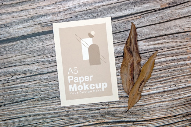 A5 papieren wenskaart mockup met droge bladeren op houten achtergrond