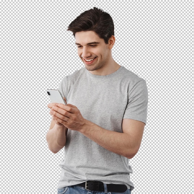 Afbeelding van een knappe man die berichten schrijft, op sociale media chatten en glimlachend het scherm van zijn mobiele telefoon lezen terwijl hij over een witte muur staat