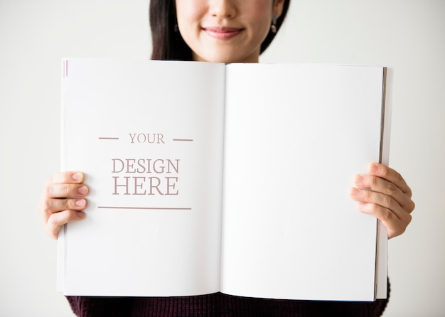 アジアの女性が空白の雑誌を抱えている