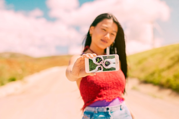 Asian woman presenting smartphone mockup in nature