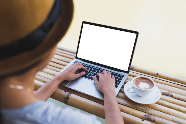 Asian women are typing a laptop keyboard mockup on a bamboo table