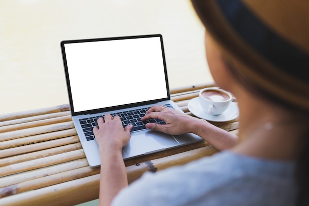 Asian women typing on laptop mockup on a bamboo table