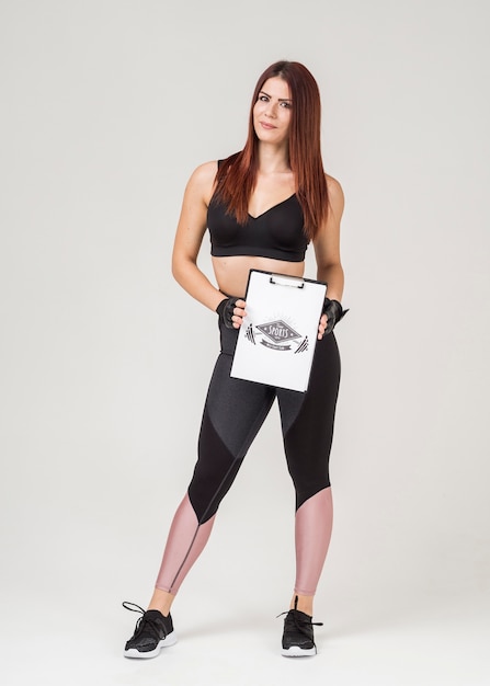 Атлетическая женщина в спортзале одевает держать блокнот