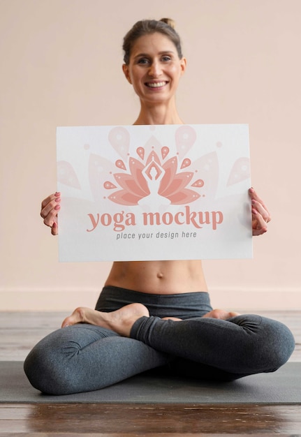 PSD giovane donna atletica che tiene banner mock-up mentre fa yoga