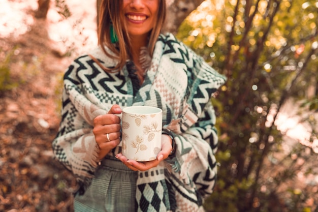 Concetto di autunno con la tazza della holding della donna