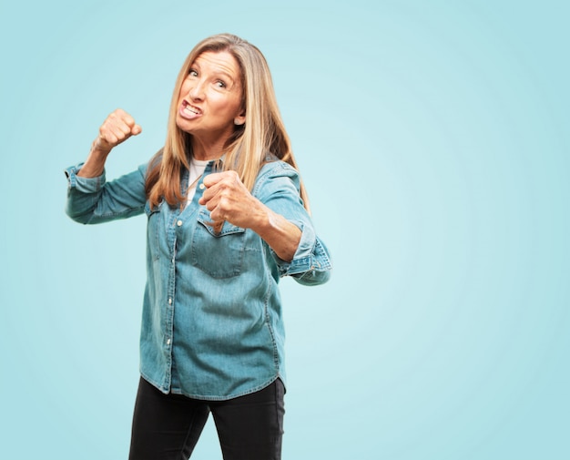 Beautiful senior woman with an angry, aggressive and menacing pose, ready for the fight