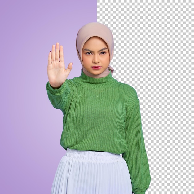 Beautiful serious Asian woman in a green sweater standing with outstretched hand showing stop gesture