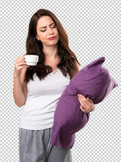 Beautiful young girl with a pillow holding a cup of coffee