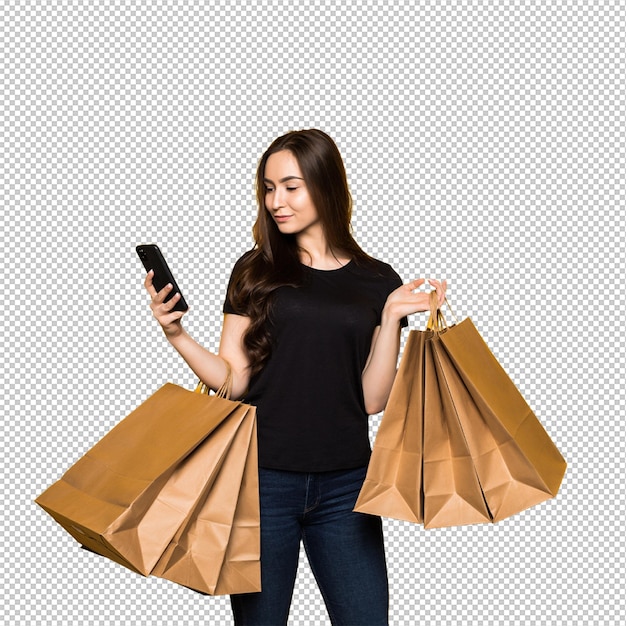 ショッピングバッグを持った美しい若い女性が黄色い壁でスマートフォンを使ってショッピングをしているショッピング依存症ファッション