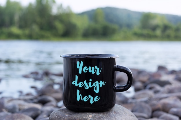 Black campfire mug mockup with stony river bank