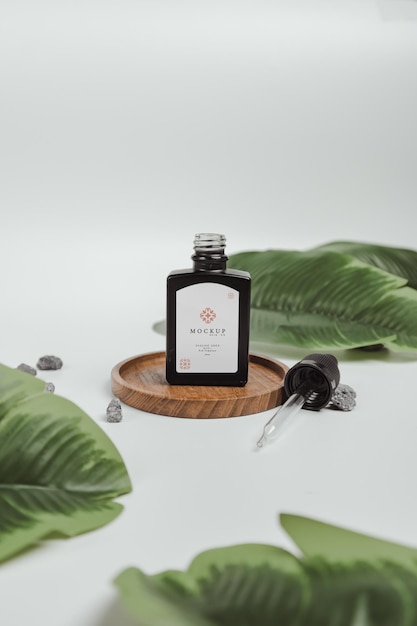 Черная косметическая бутылка сыворотки Макет с белым фоном и листьями