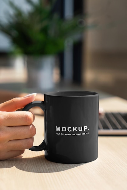 A black mug at office table in the hand