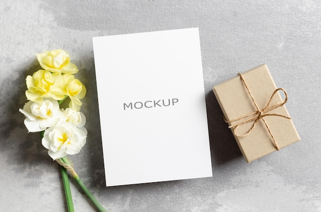 Blank greeting card mockup with gift box and daffodils flowers