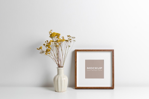 Blank square frame mockup with dry flowers decoration in white room interior