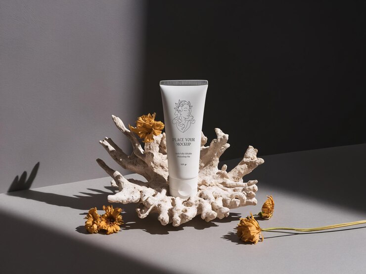 PSD blank white cosmetic tube product mockup on dry coral next to dried flowers