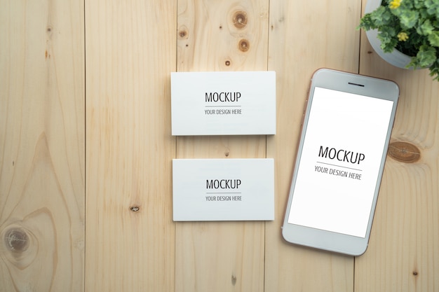 PSD blank white screen smartphone and business card mockup on wood table