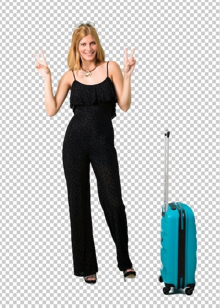 PSD Белокурая девушка путешествуя с ее чемоданом усмехаясь и показывая знак победы