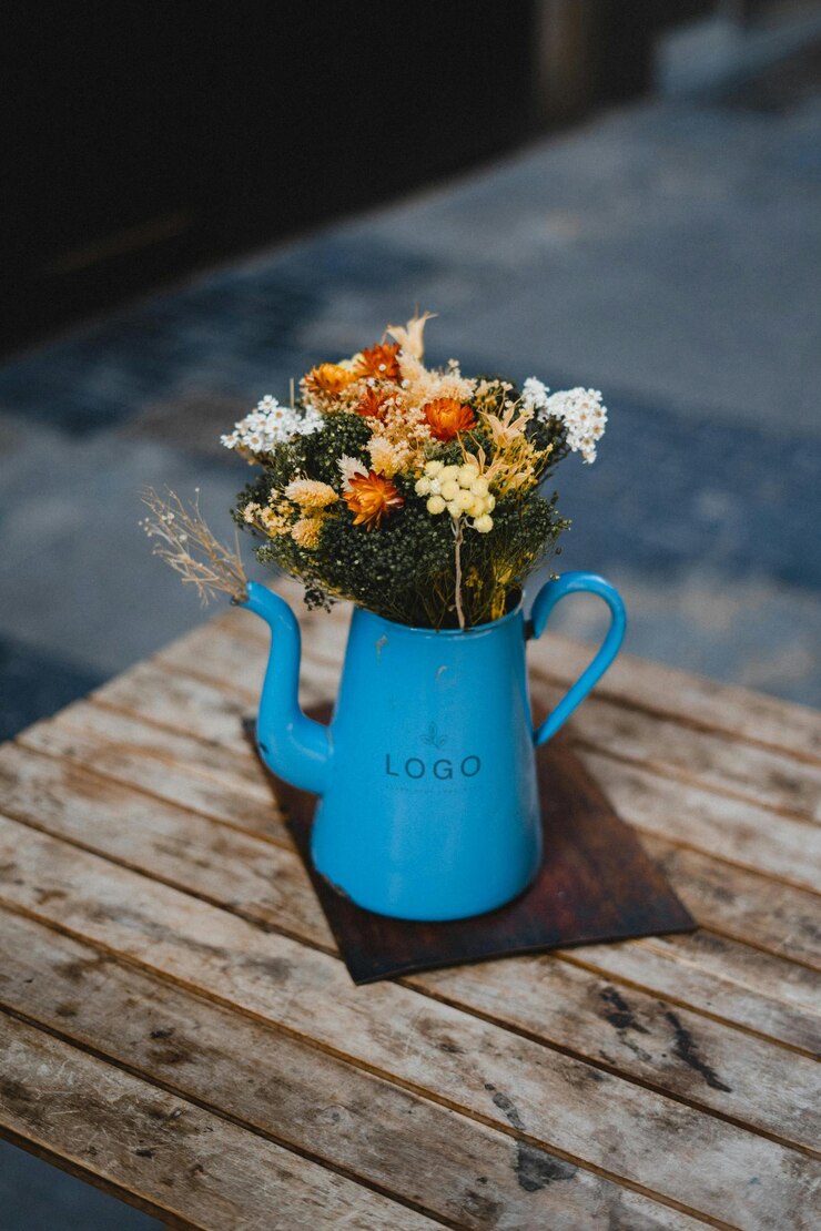 PSD a blue teapot filled with colorful flowers on a wooden table