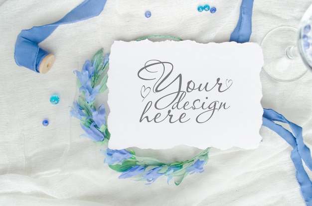 シルクリボン、クリスタル、花嫁の花輪で飾られた青い結婚式招待状のモックアップ