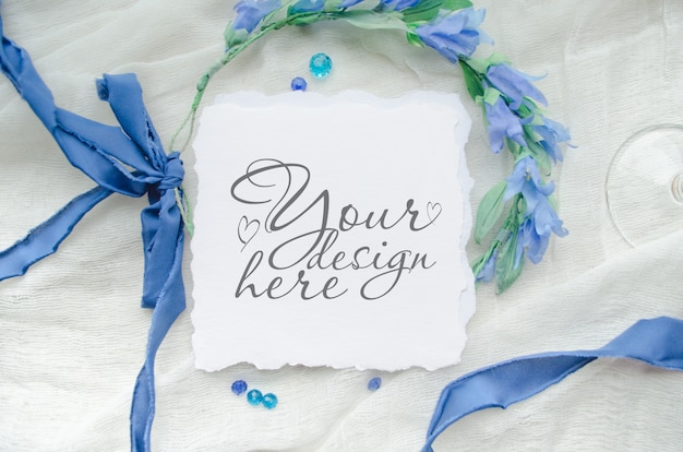 Blue wedding invitation mockup decorated with silk ribbon, crystals and bride wreath