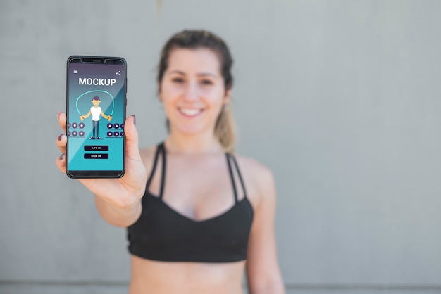 PSD blurred woman in sport clothes holding mobile mock-up