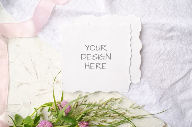 Bruiloft mockup kaart met roze bloemen en delicate zijden linten op een witte ruimte