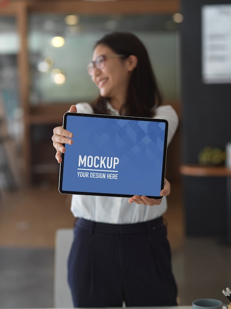 PSD businesswoman showing mock up blank screen tablet while standing in the office room , clipping path