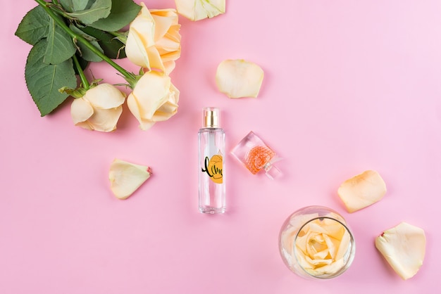 PSD butelki perfum z kwiatami na różowym tle