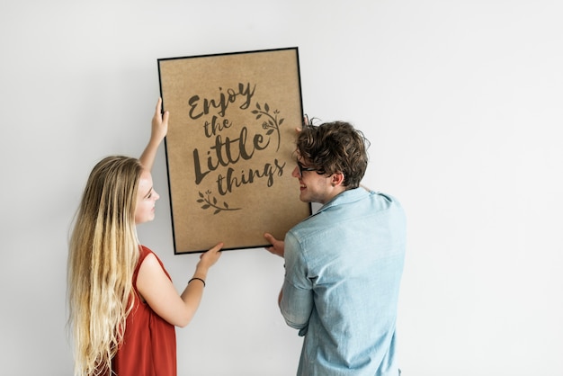 PSD caucasian couple hanging a frame on white wall