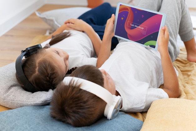 PSD bambini che utilizzano il mockup di tablet e cuffie