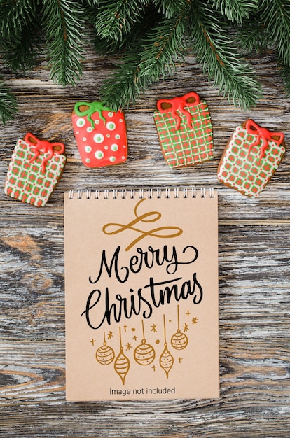 christmas background with brown notebook mockup, gingerbread cookies and fir tree