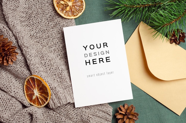 Christmas greeting card mockup with envelope, dry oranges and pine tree branches with cones