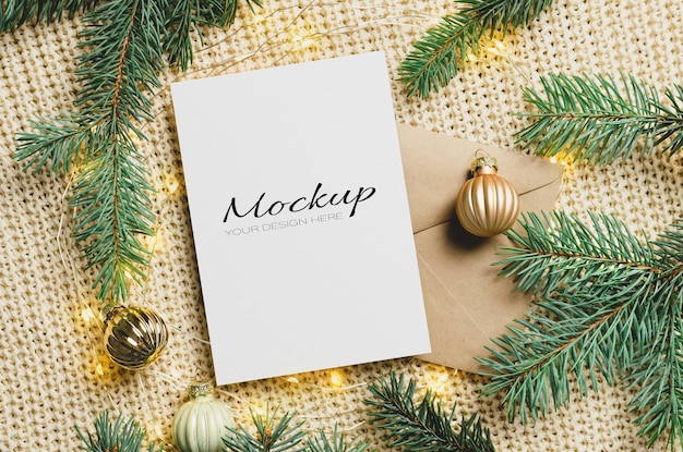 Christmas greeting card mockup with envelope, festive decorations and fir tree branches with lights