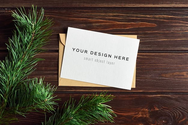 Christmas greeting card mockup with pine branches over wooden background