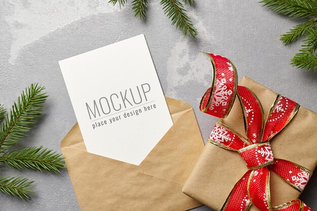 PSD christmas greeting or invitation card mockup with envelope, gift box and fir tree branches