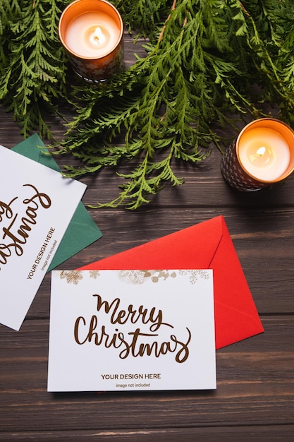 Christmas letters and greeting cards lie on brown wooden table with fir branches and candles Mockup