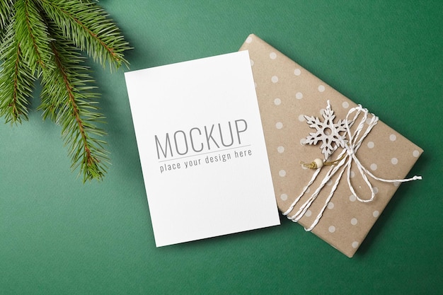 Christmas or new year greeting card mockup with decorated gift box and green fir tree branch