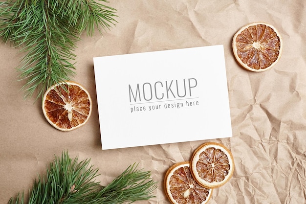 Christmas or New Year greeting card mockup with dry oranges and pine tree branches on craft paper