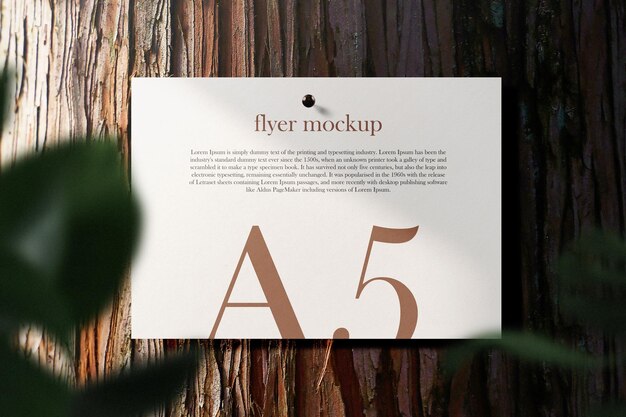 Clean minimal A5 flyer mockup pin on bark wood table with leaves.