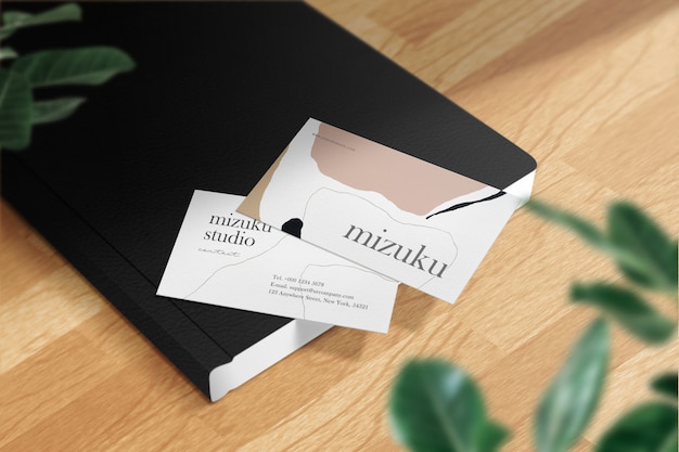 Clean minimal business card mockup on black book leather and leaves.