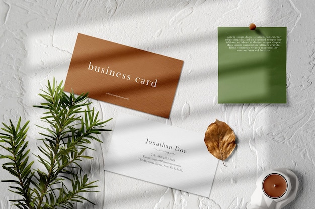 PSD mockup di biglietto da visita minimo pulito su fondo di cemento con carta e spilla per candeliere a foglia di conifere