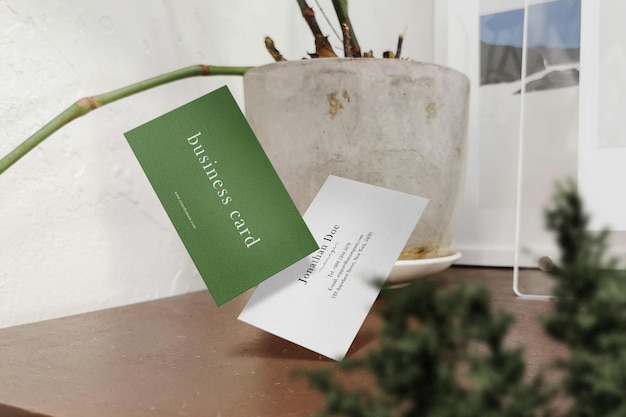 Чистый минимальный макет визитной карточки, плавающий на деревянном столе с растительным фоном psd-файл